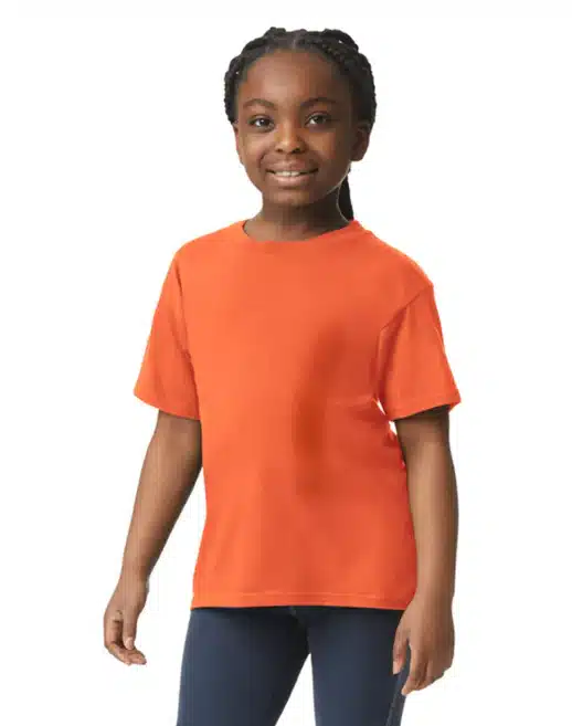 Girl in orange t-shirt and navy pants stands against a white background.
