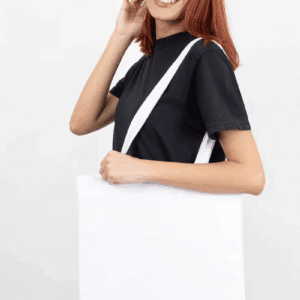 Smiling woman with auburn hair wearing a black t-shirt and white cotton canvas bag.